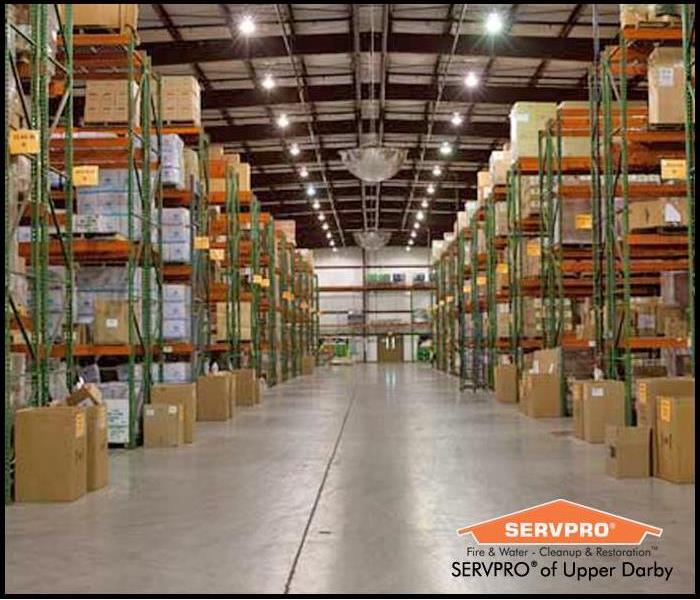 Looking down the aisle of a warehouse with cardboard boxes stacked on multiple rows