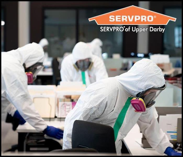 SERVPRO professional in Personal Protection Equipment cleaning and disinfecting a commercial property