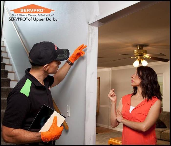 SERVPRO technician pointing to an area of smoke damage inside the home while the homeowner looks on